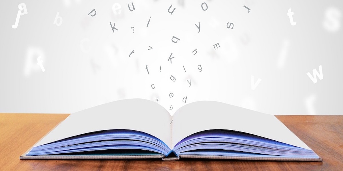 Image of open book with letters flowing around