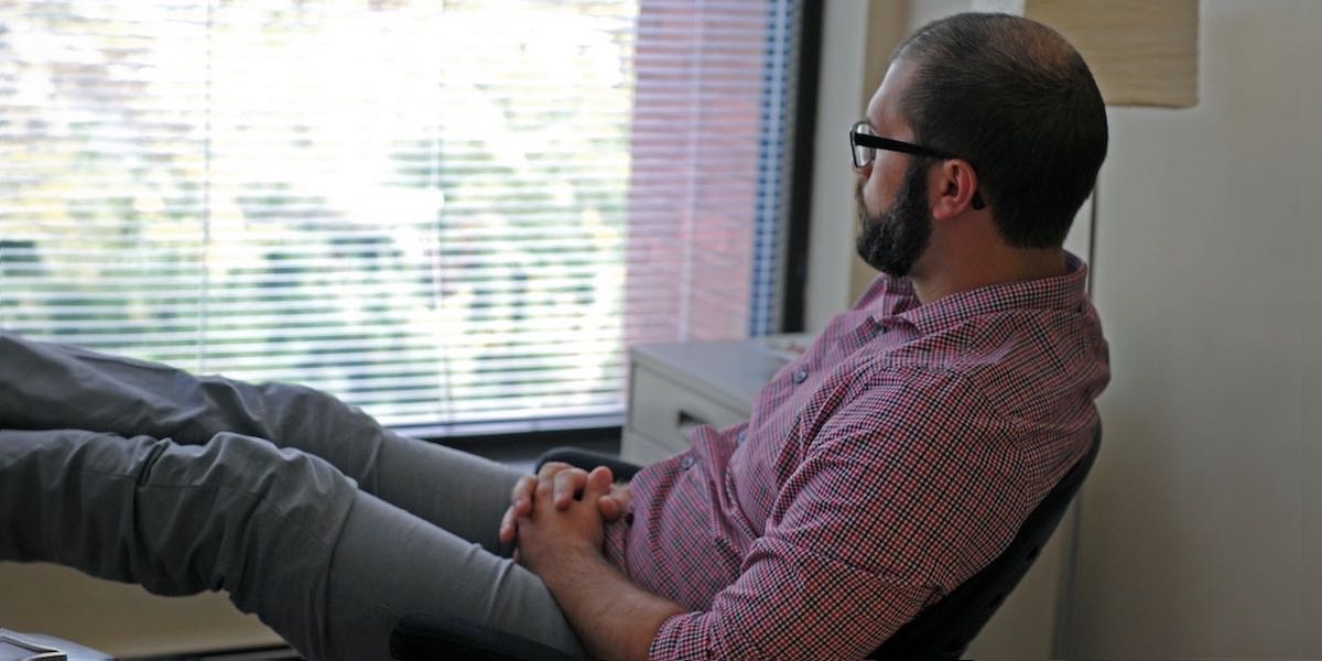Man looking out window leaning back in chair