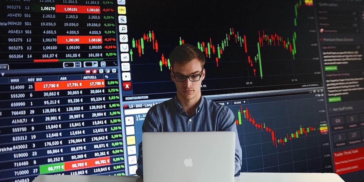 Man trading stocks with charts behind him