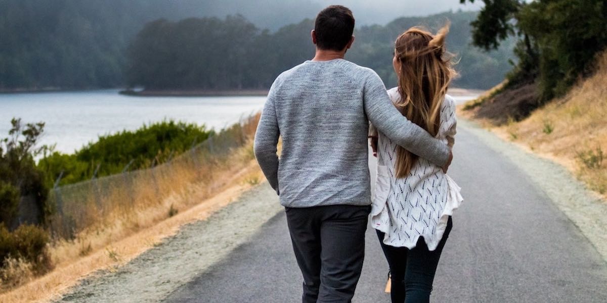 Couple walking arm-in-arm by a river
